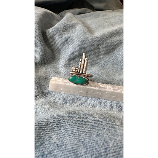 Ring with green stone and metallic band on a gray fabric background