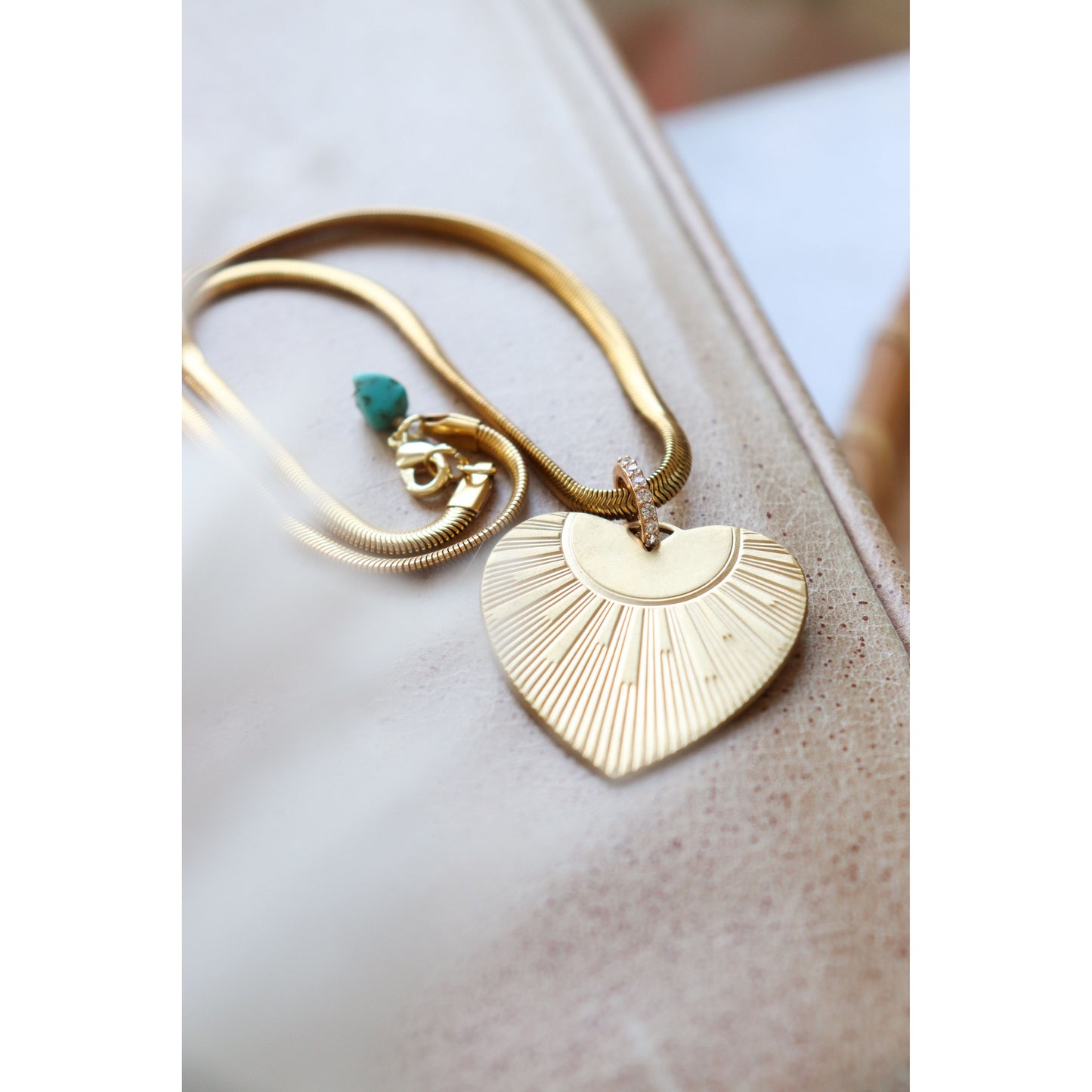 Gold heart necklace with rhinestone toggle laying on surface.