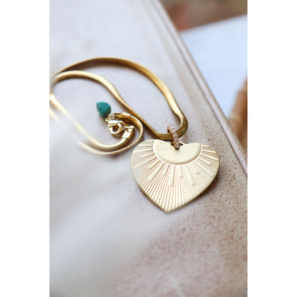 Gold heart necklace with rhinestone toggle laying on surface.