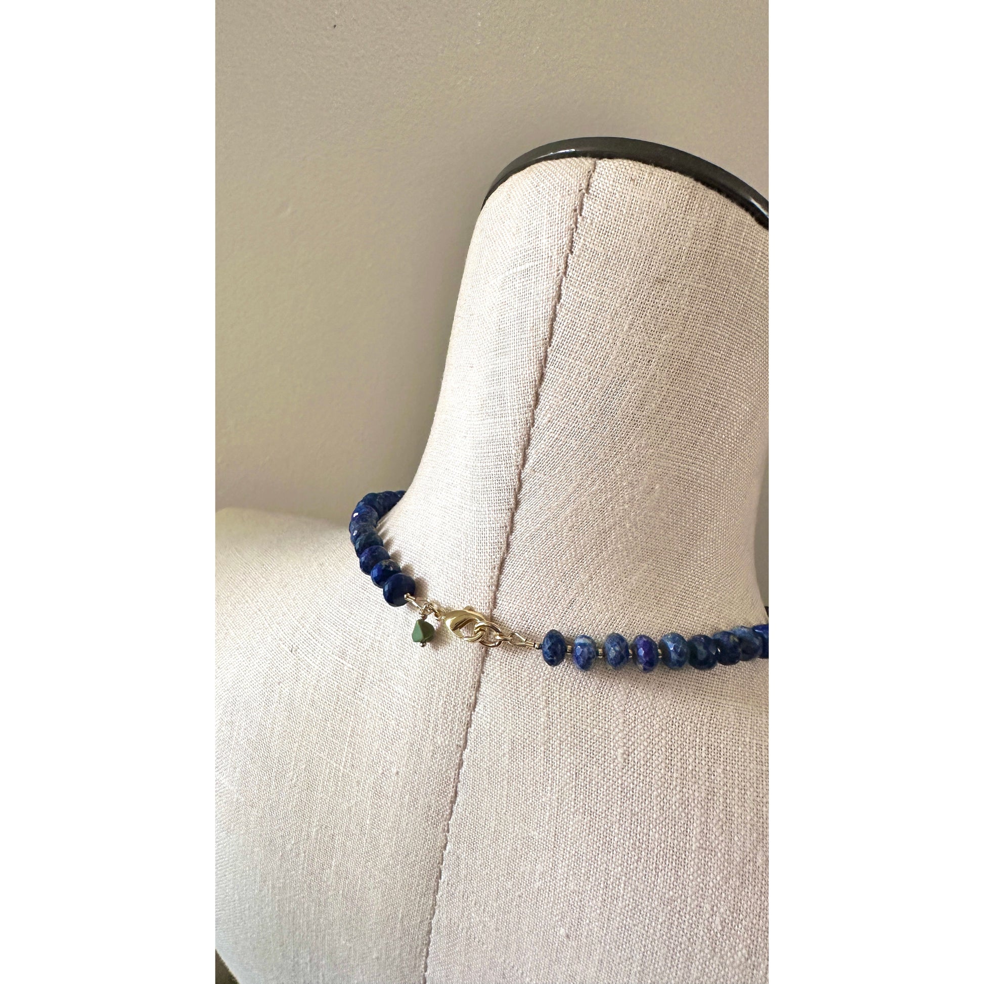 Blue beaded bracelet on a mannequin bust against a plain background