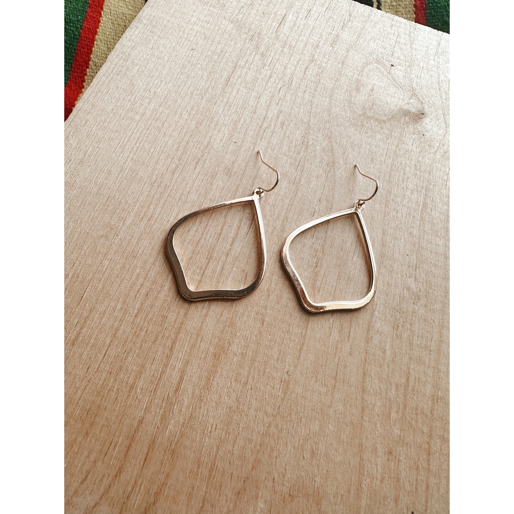 Gold hoop earrings on a wooden surface