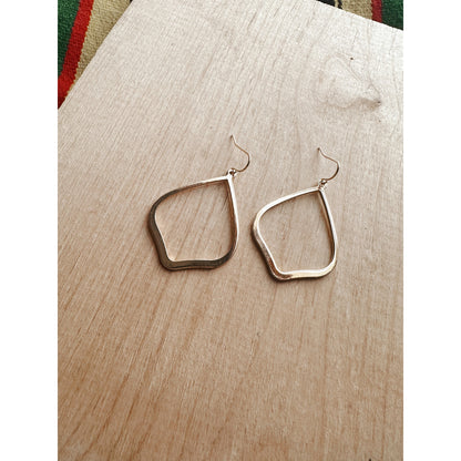 Gold hoop earrings on a wooden surface