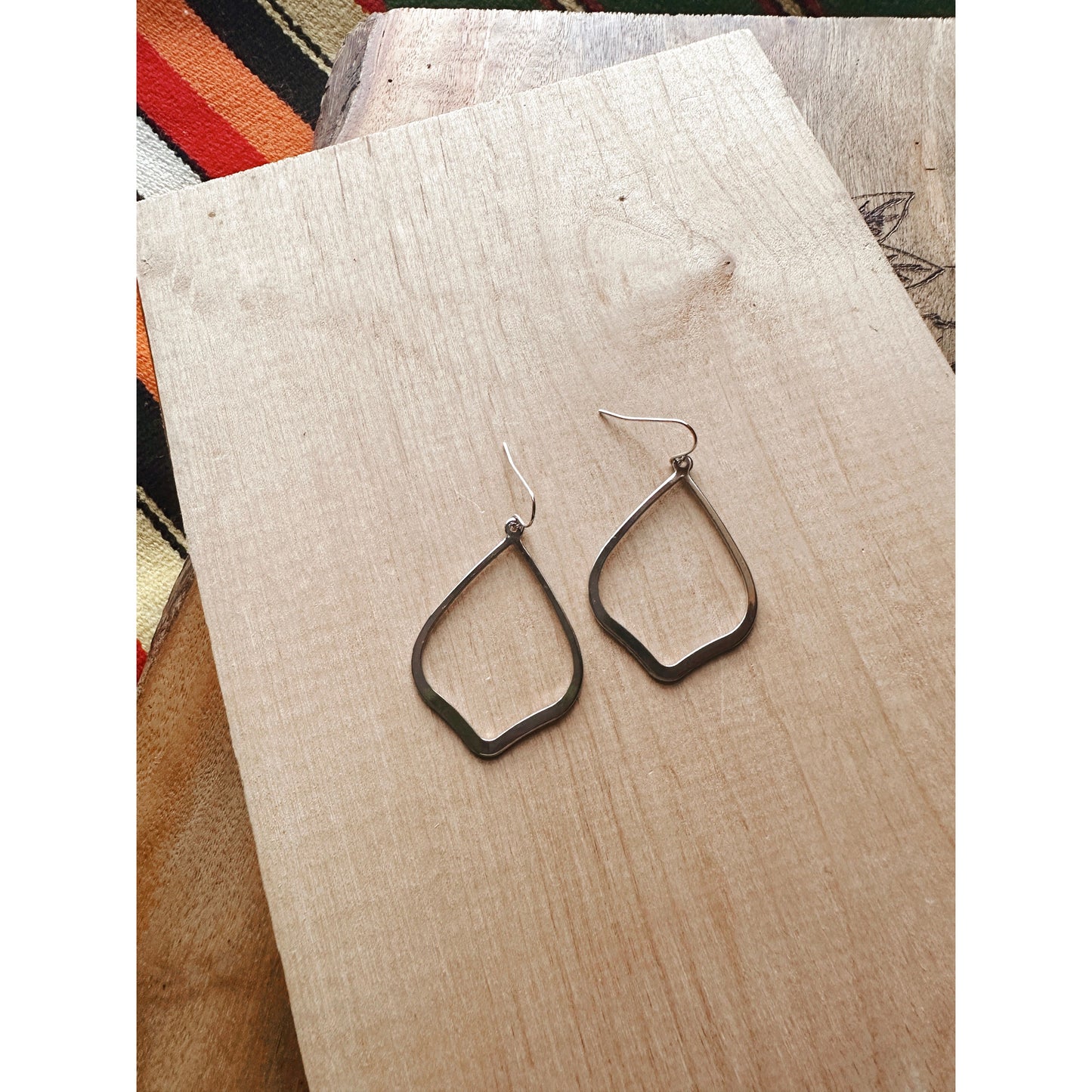 silver earring laying on wood