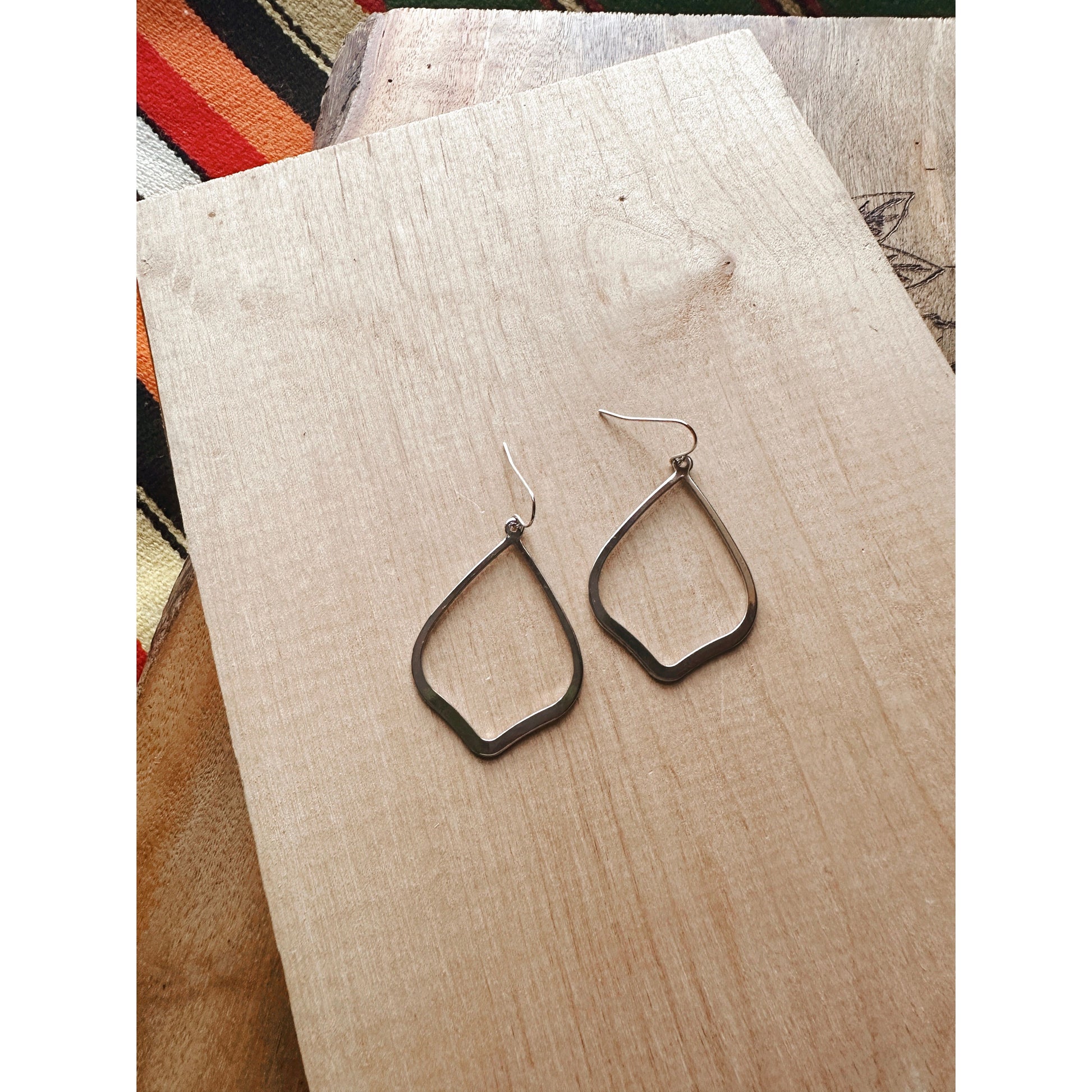 silver earring laying on wood