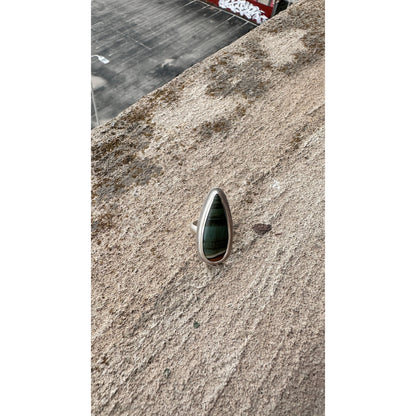 Silver ring with a green stone on a textured surface