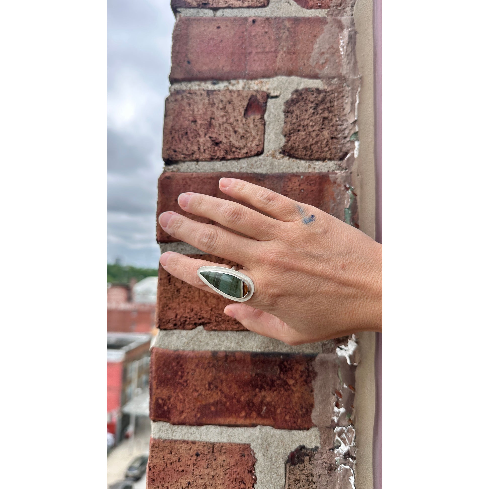 Hand wearing a ring on a brick wall background