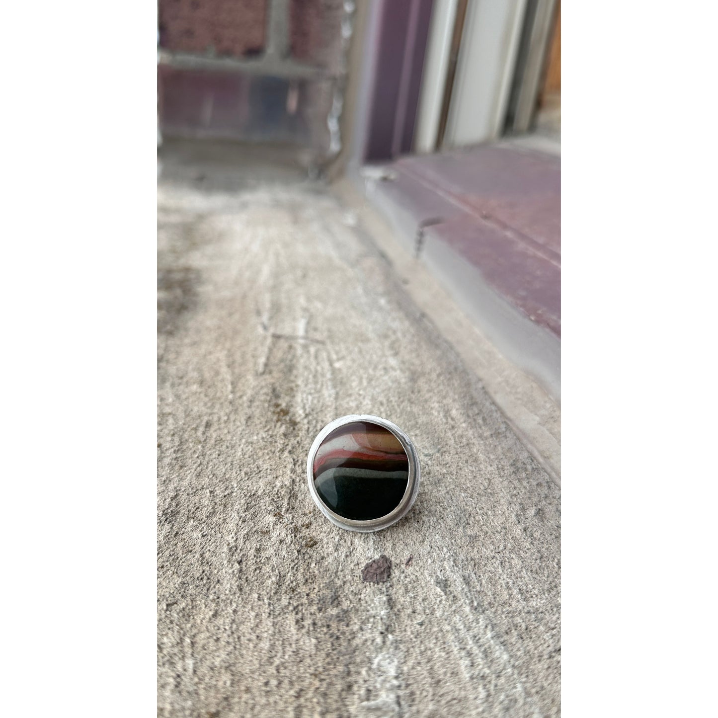 Silver ring with a black stone on a textured surface
