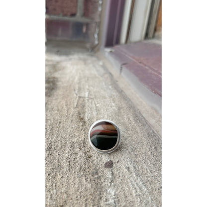 Silver ring with a black stone on a textured surface