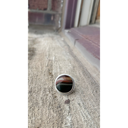 Silver ring with a black stone on a textured surface
