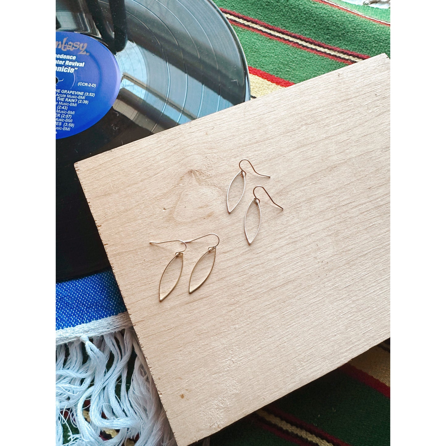 Gold and Silver earrings on a wooden block with a colorful background