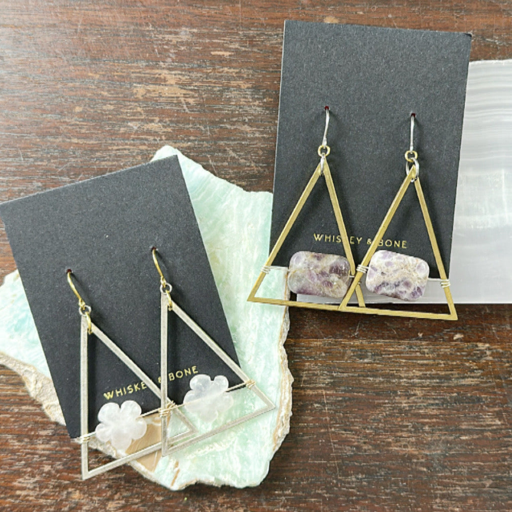 Geometric gold earrings with stone accents on Whiskey Bone display cards against a wooden background.