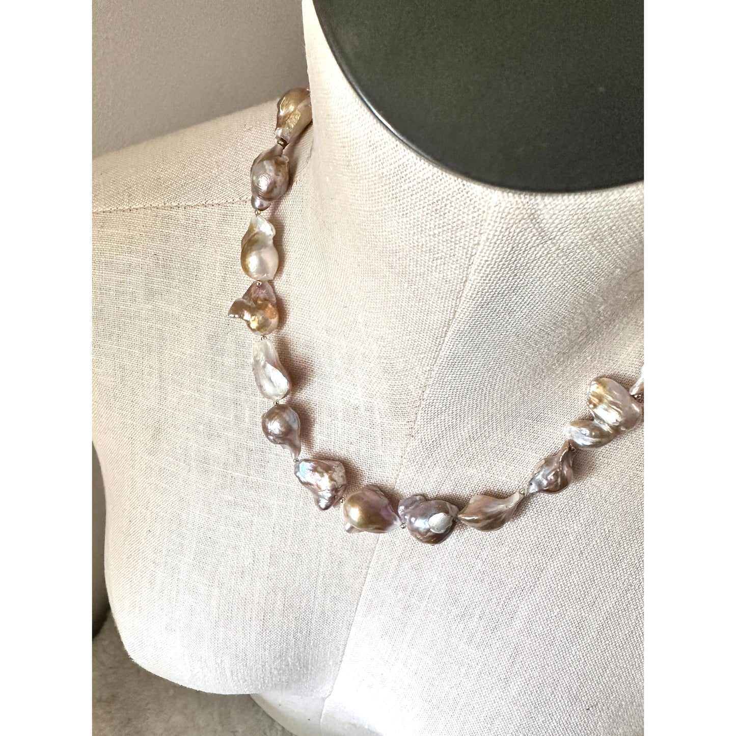 Pearl necklace on a mannequin bust against a neutral background