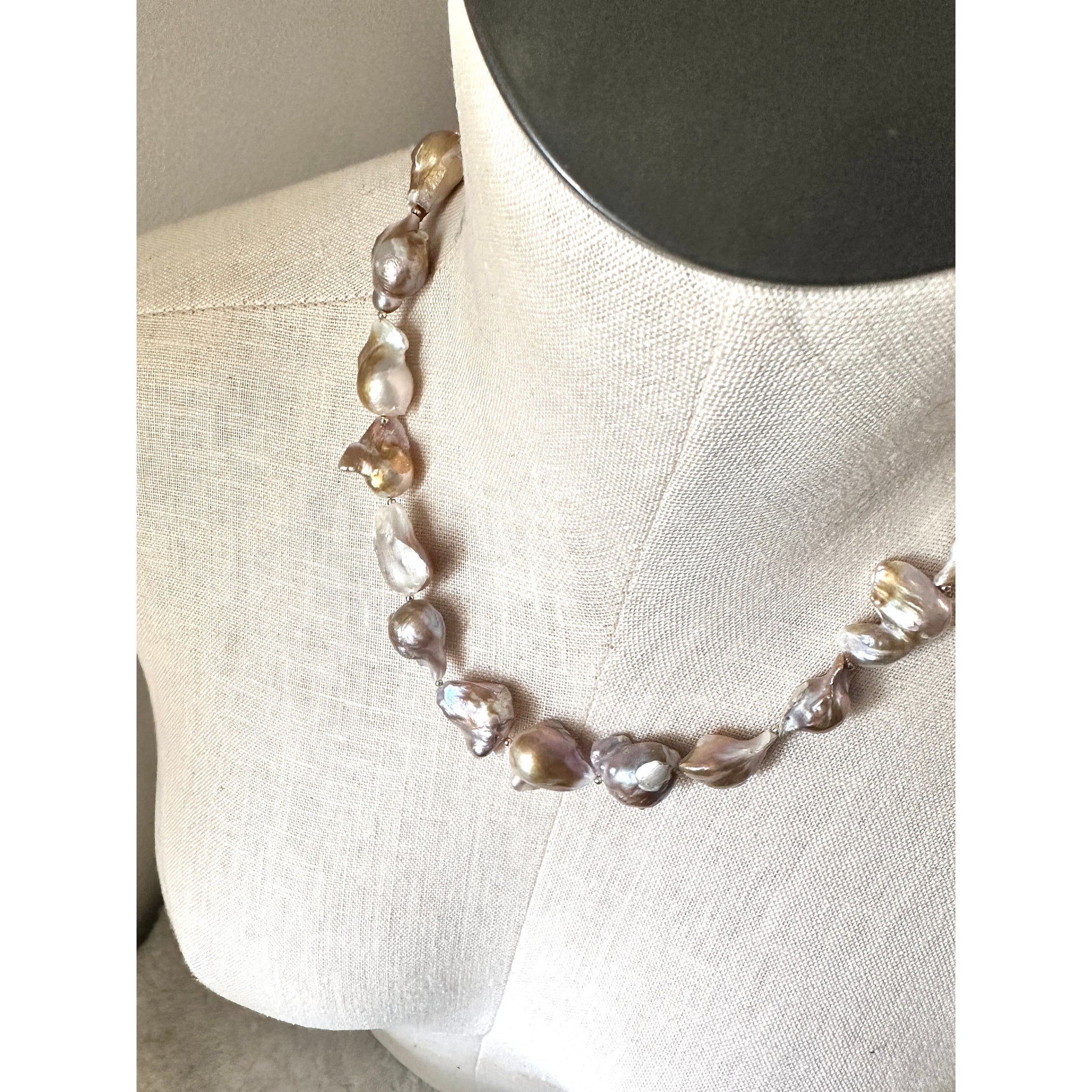 Pearl necklace on a mannequin bust against a neutral background