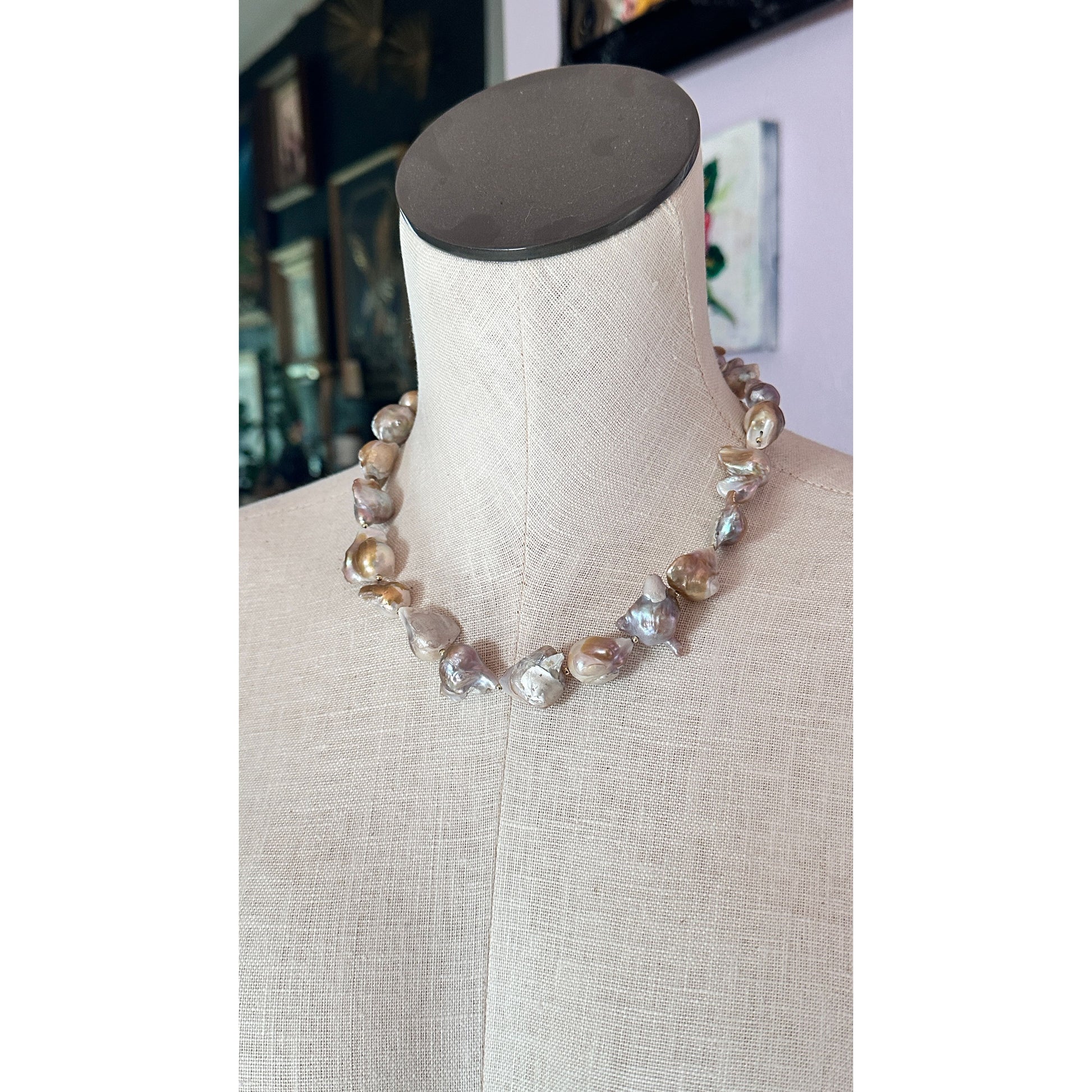 Necklace with large beads on a mannequin bust against a blurred indoor background