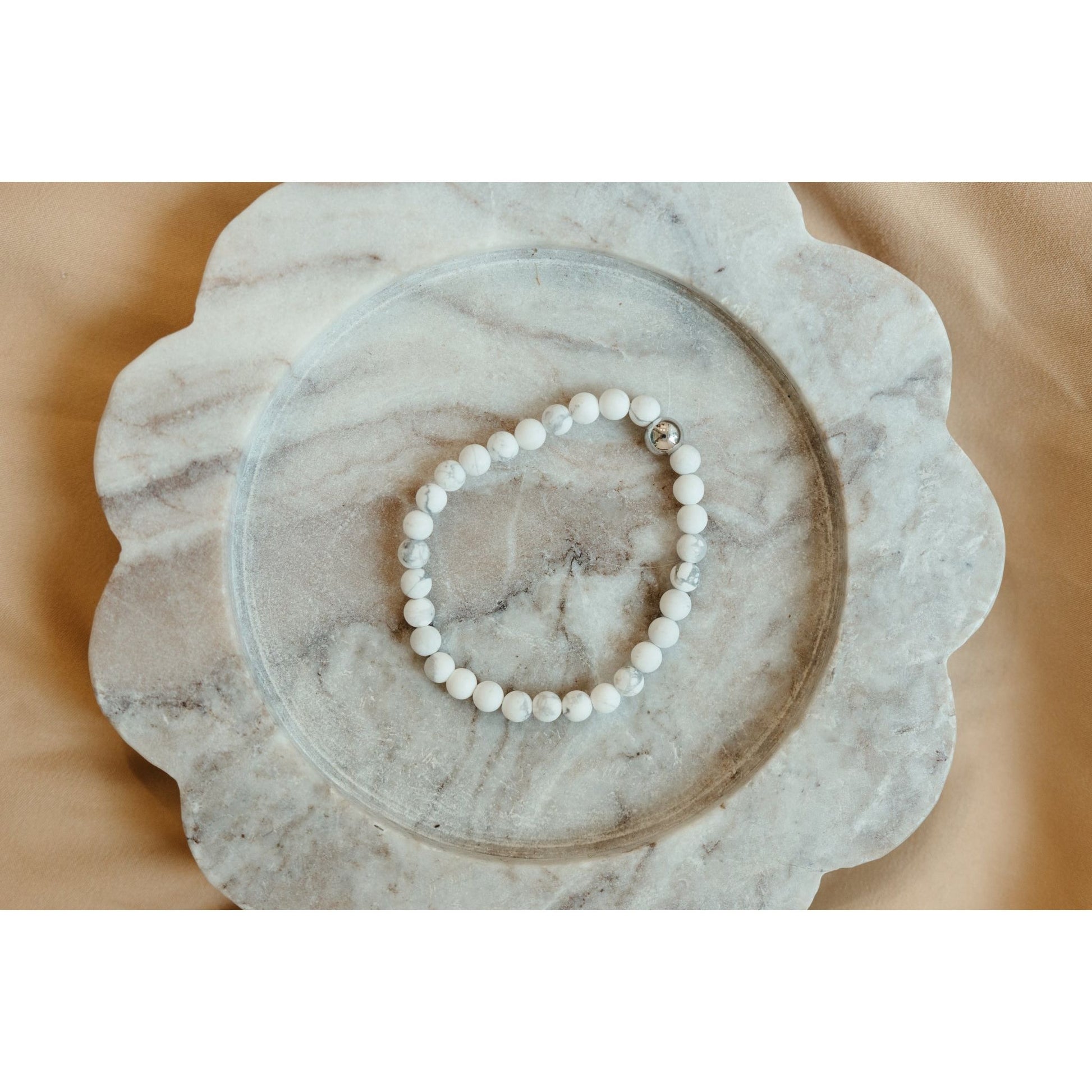 White beaded bracelet on a marble surface