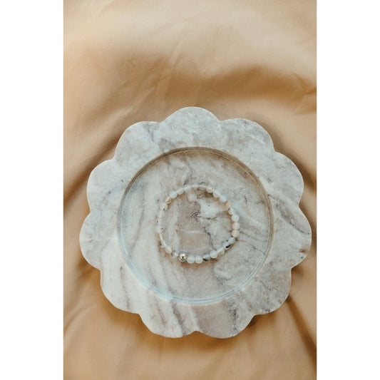 Decorative stone bowl with scalloped edge on a beige background