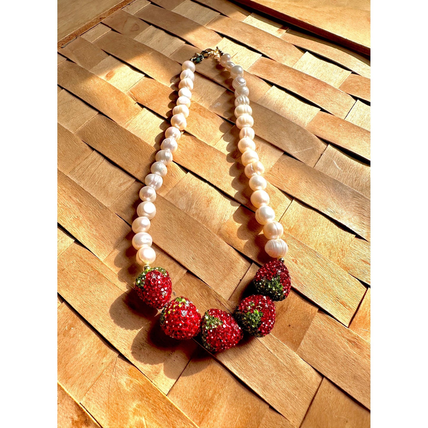 Necklace with strawberry-shaped beads on a wooden surface