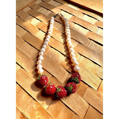 Necklace with strawberry-shaped beads on a wooden surface