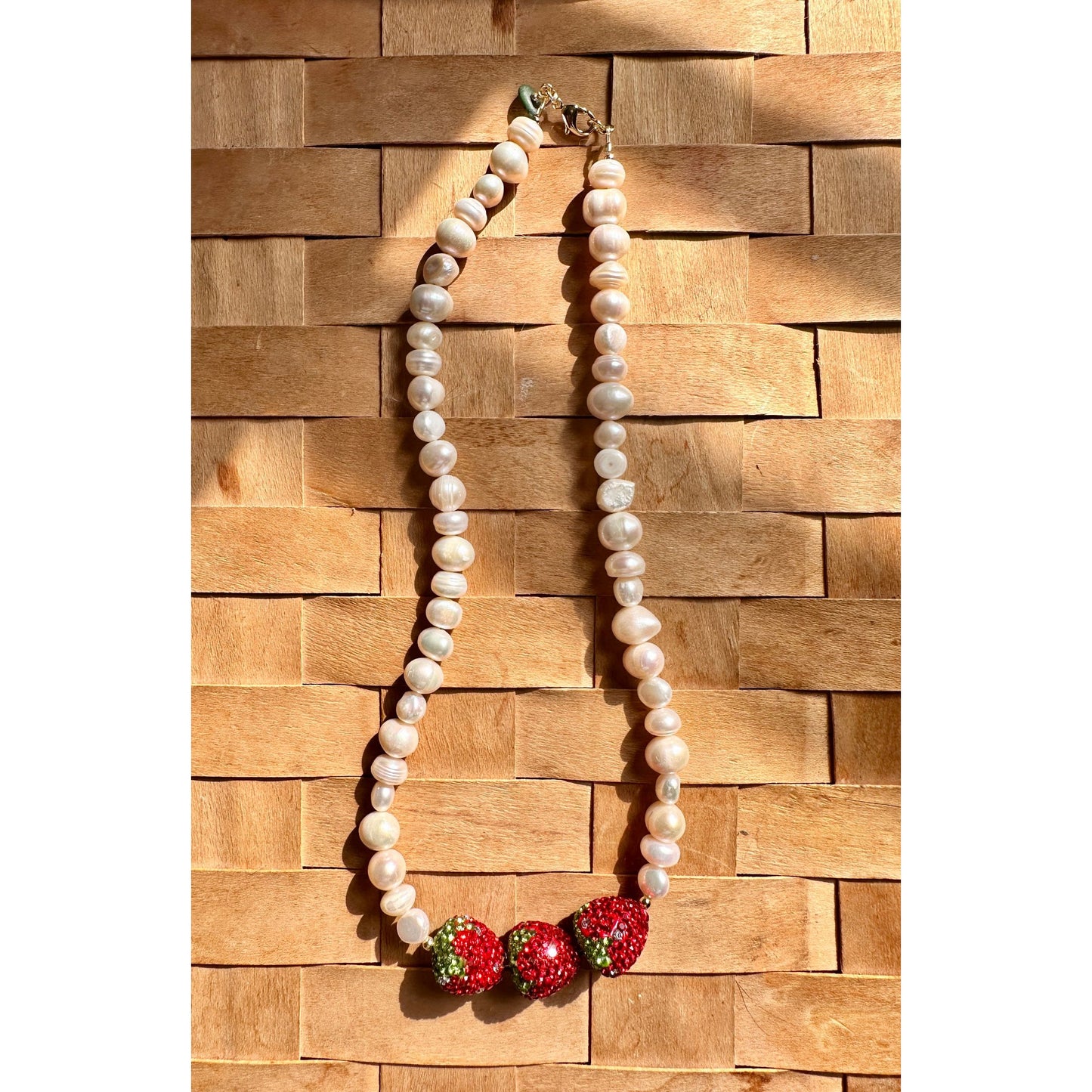 Pearl necklace with red and green accents on a wooden background