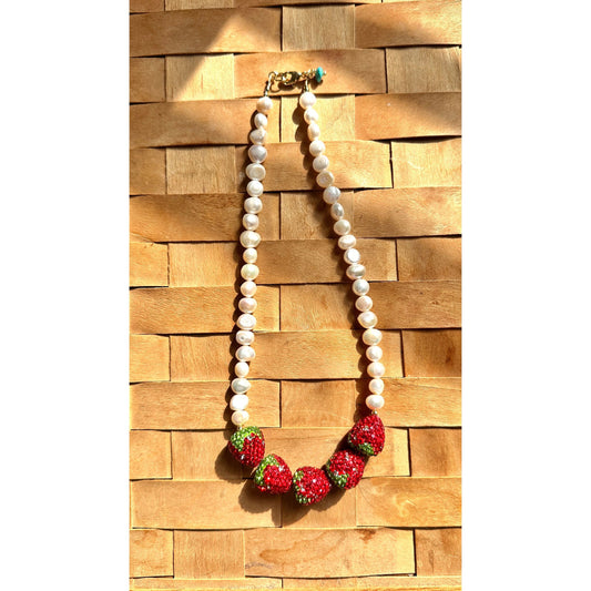 Necklace with strawberry-shaped pendants on a woven wooden surface