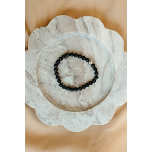 Black beaded bracelet on a marble coaster with a beige background