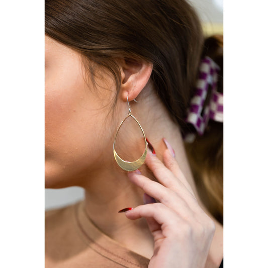 Gold earrings being worn by girl with brown hair