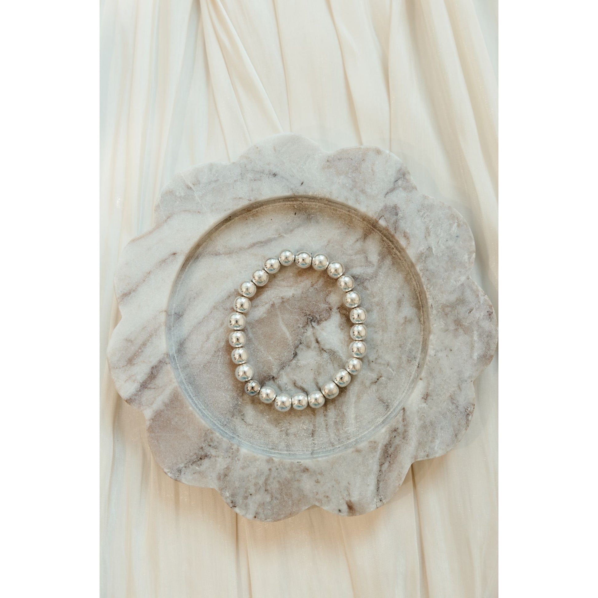 Silver bracelet on a decorative stone plate with a soft beige background