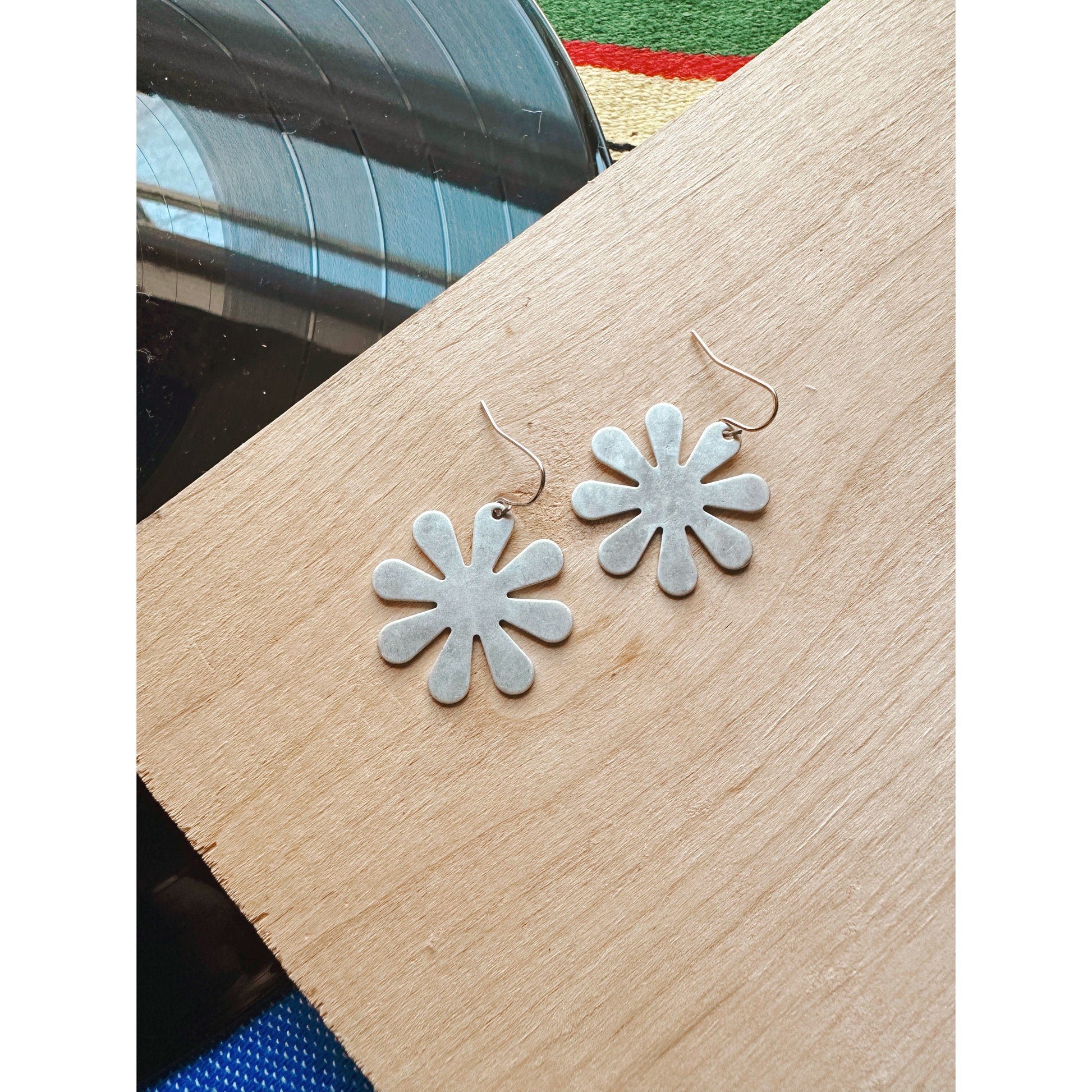 Flower-shaped earrings on a wooden surface with a blurred background