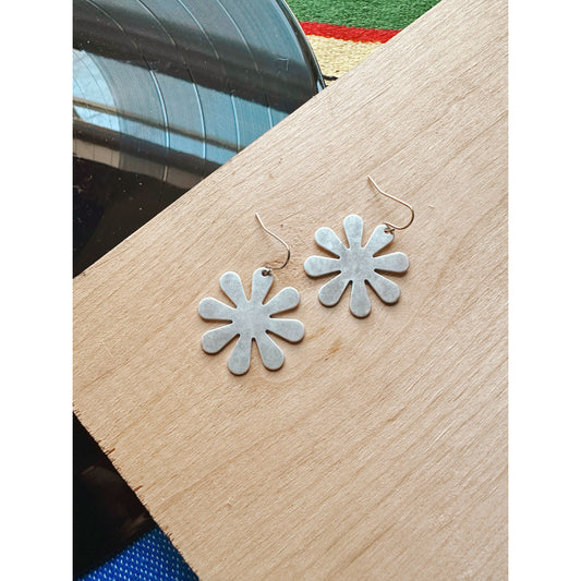 Flower-shaped earrings on a wooden surface with a blurred background