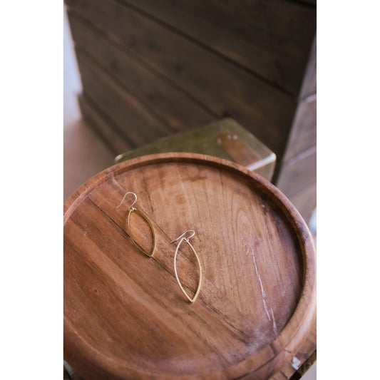Gold earrings on a wooden surface with a blurred background