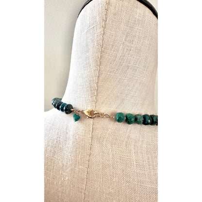 Bracelet with green beads on a mannequin arm against a neutral background