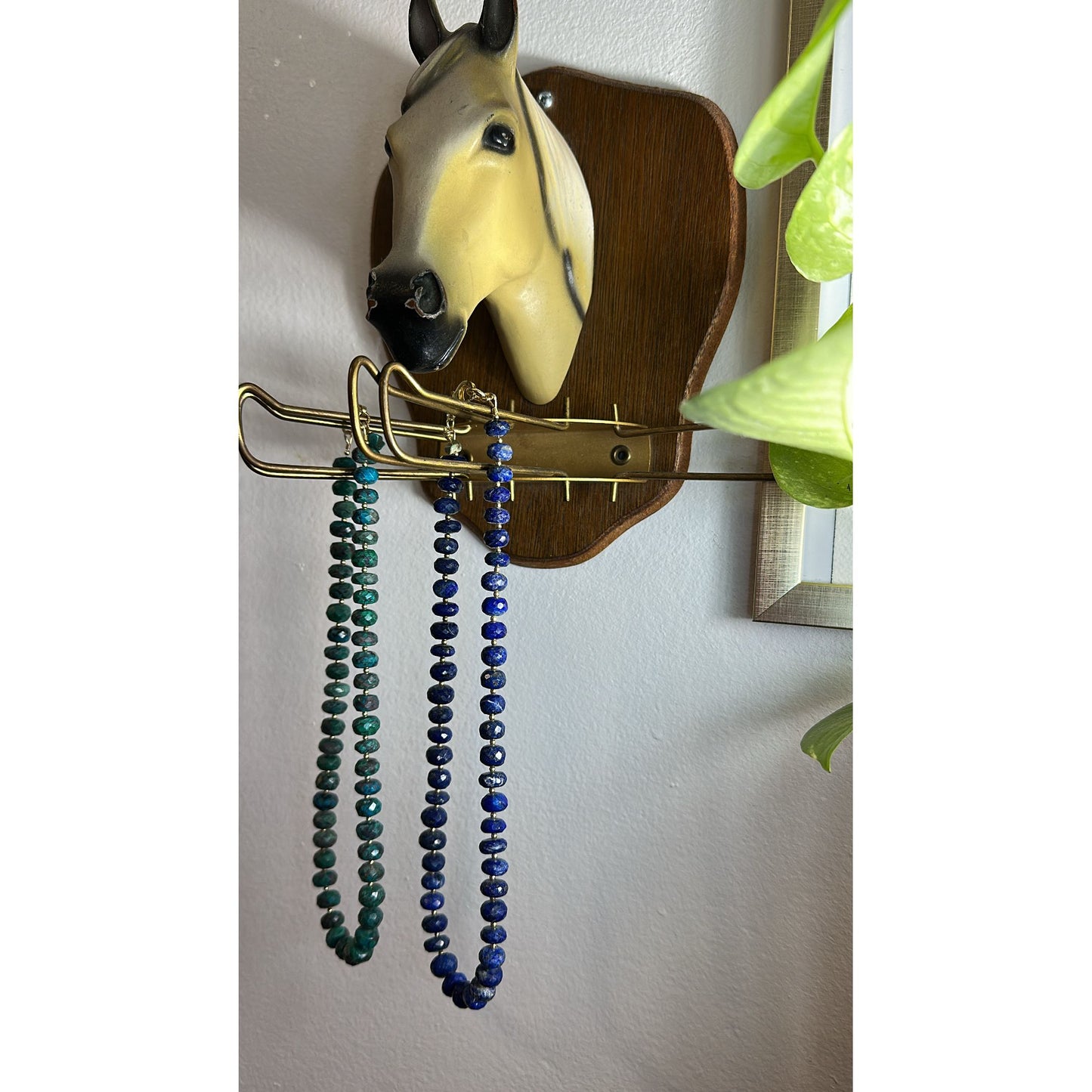 Jewelry holder with necklaces hanging on a wall-mounted horse head decoration.